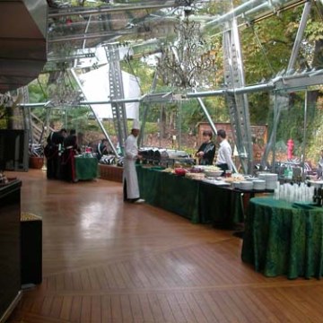 Waitstaff preparing buffet tables in a glass-walled restaurant with wooden floors.