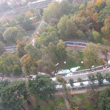 Aerial view of a winding path through a park with dense trees and scattered structures.