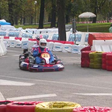 Person in a go-kart racing on an outdoor track with colorful tire barriers.