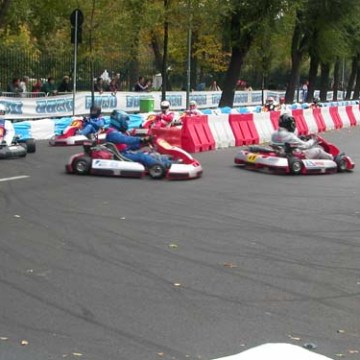 Go-kart race on a track with barriers and trees in the background.