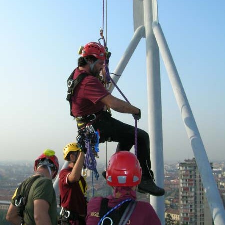 Group of people in safety gear climbing a metal structure overlooking a cityscape.