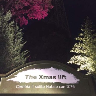 Sign reads 'The Xmas lift' with trees and pink lighting at night.