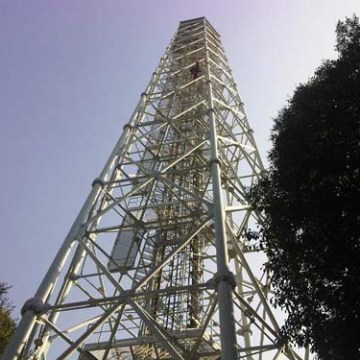 Looking up at a tall metal lattice tower with a clear sky backdrop.