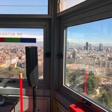 View of city skyline through large windows with a solar location map and equipment inside.
