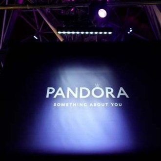 Dark stage with illuminated 'PANDORA' sign and 'Something About You' slogan.