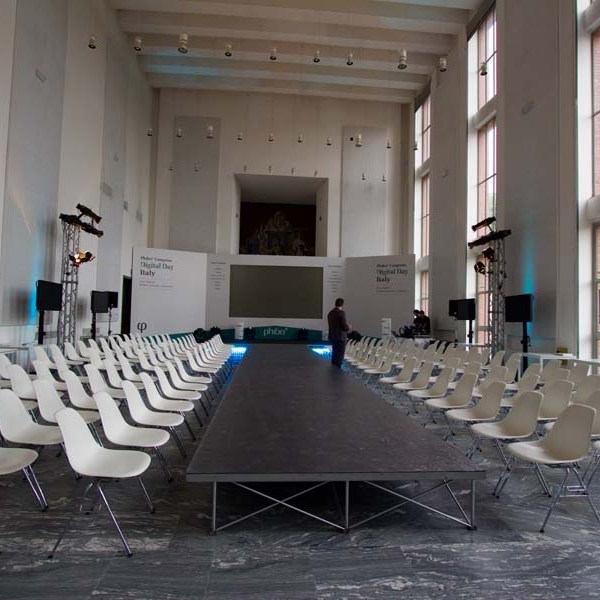 Empty fashion show runway with white chairs in a large hall.