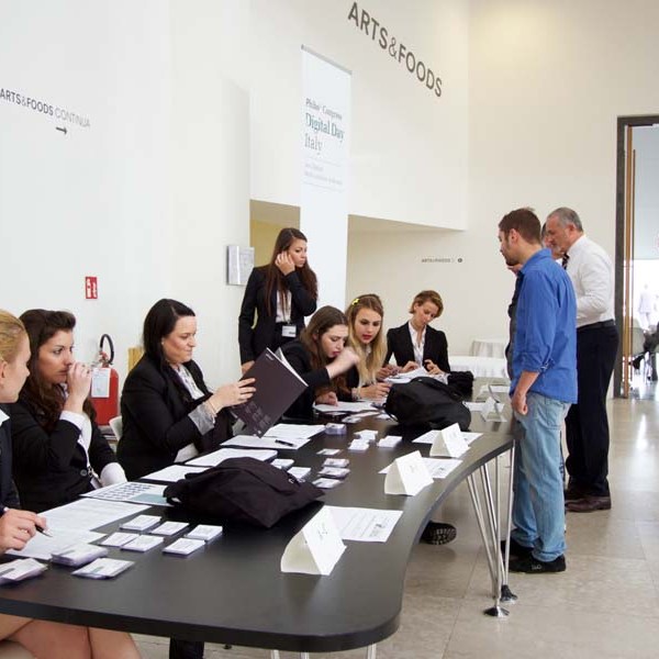 People at a registration desk for an event, with signage and name tags visible.