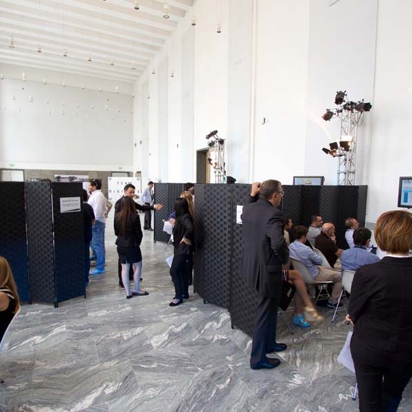 People gathered in a bright room with partitions and a screen on the right.