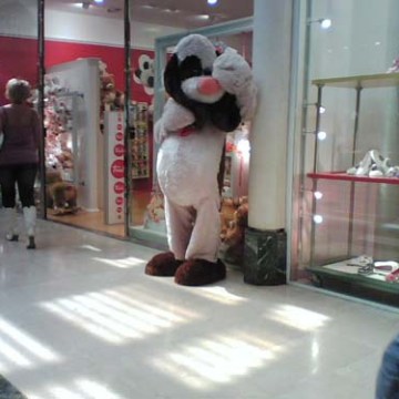 Person in dog costume standing in a shopping mall near a storefront.