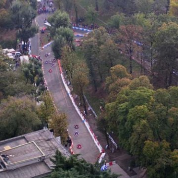 Aerial view of a winding road through a forested park with people and barriers along the path.