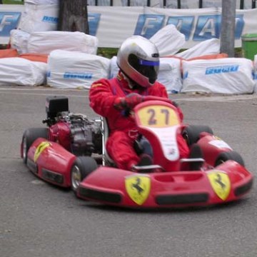 Person in red racing suit driving a go-kart on a track.