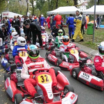 People in racing suits and helmets on go-karts lined up for a race.