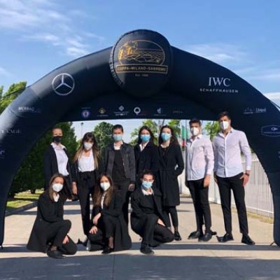 Group of people in masks under a branded inflatable arch outdoors.