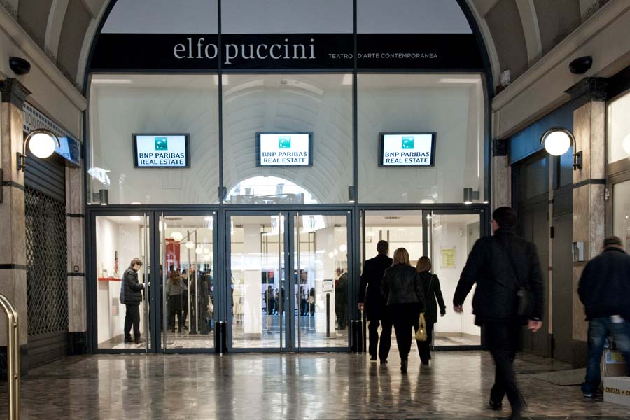 Entrance to a building with glass doors and people walking inside.